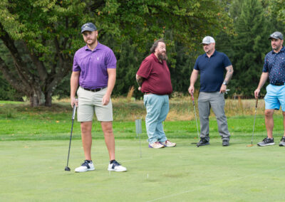 Four men playing golf for fundraiser event